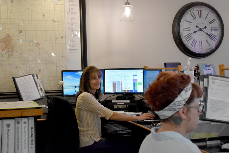 Smiling All-Pro Plumbing office staff working on computers at the front desk, representing efficient customer service and scheduling in Kokomo, IN