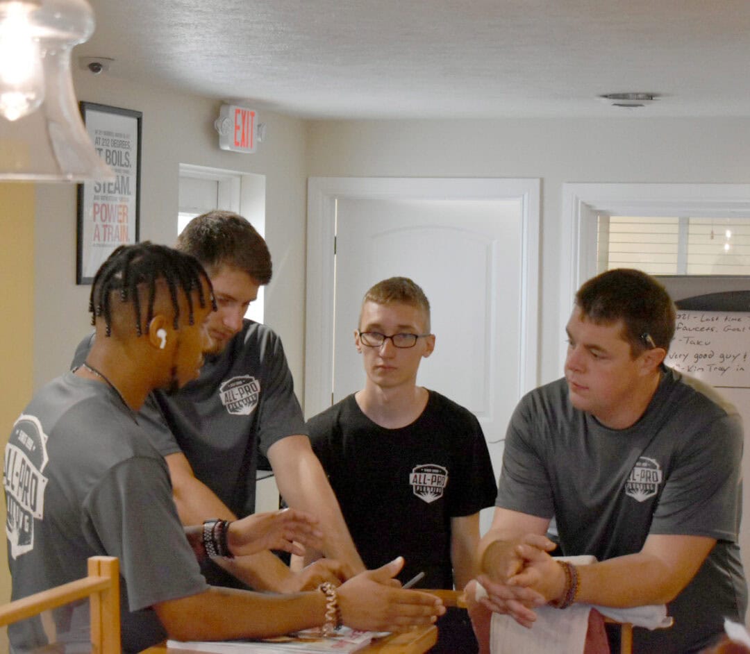 A group of All-Pro Plumbing technicians and plumbers collaborating and planning in their Kokomo office for a repair job