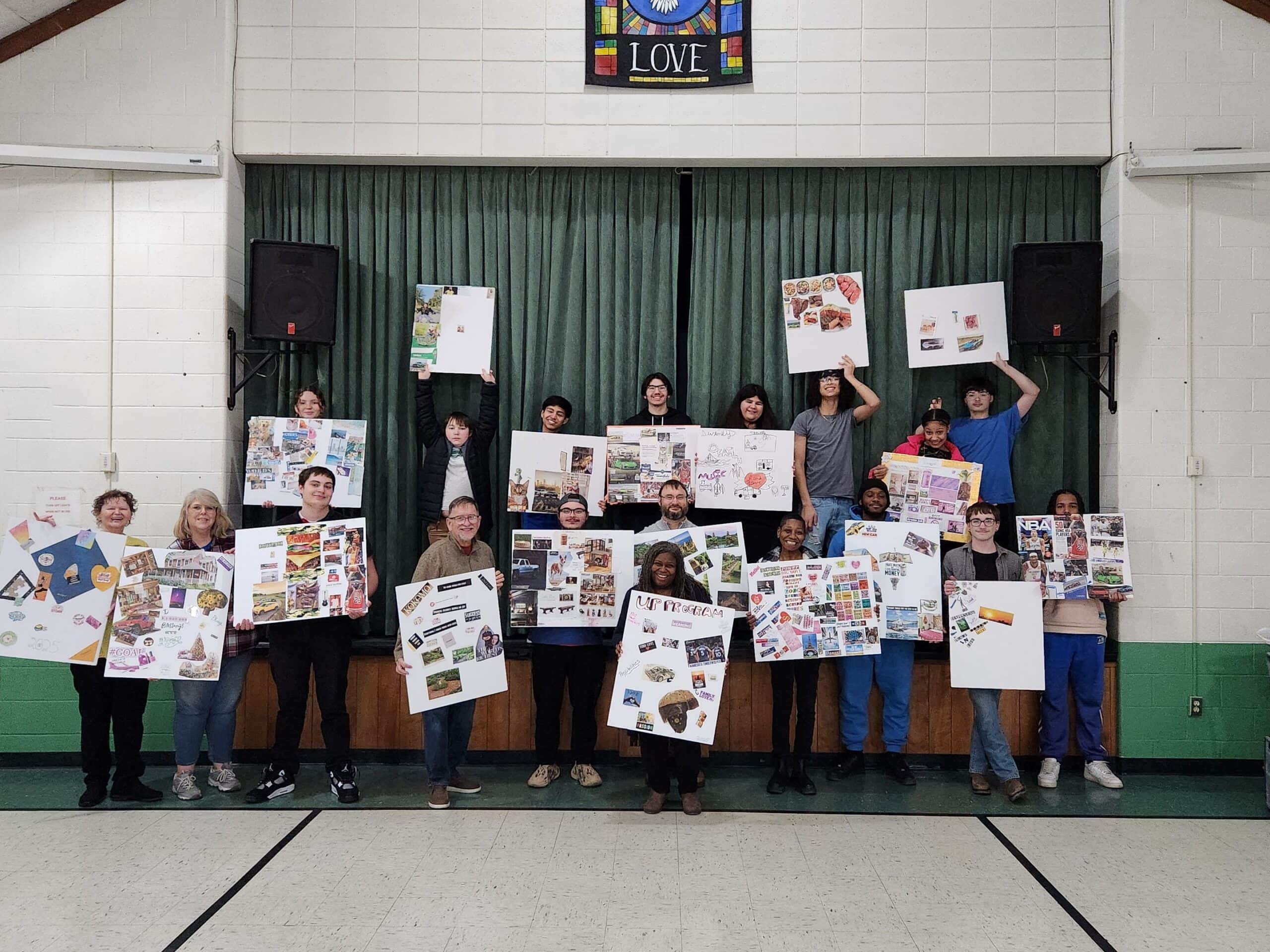 A group of teenagers and adults holding up their vision boards at a teen UP Program event sponsored by All-Pro Plumbing in Kokomo, IN