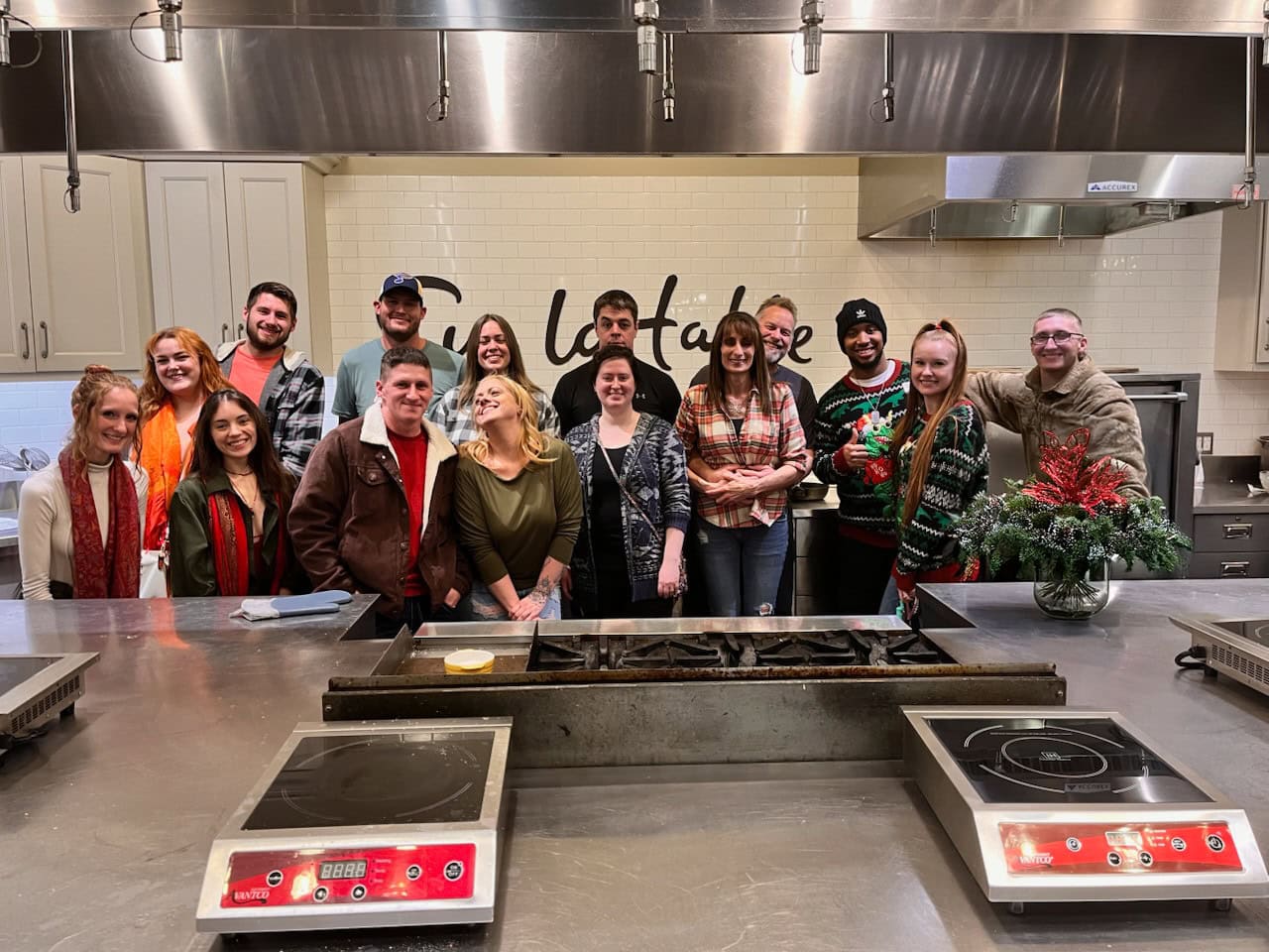 The All-Pro Plumbing team smiling in a cooking class at Sur la Table for their 2023 holiday party, representing a fun and supportive work family in Kokomo, IN