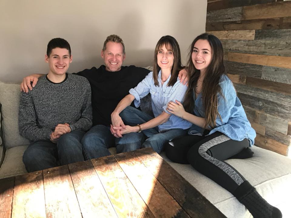 The Tracy family, owners of All-Pro Plumbing, smiling together indoors on a couch, representing the family-owned nature of the business in Kokomo, IN