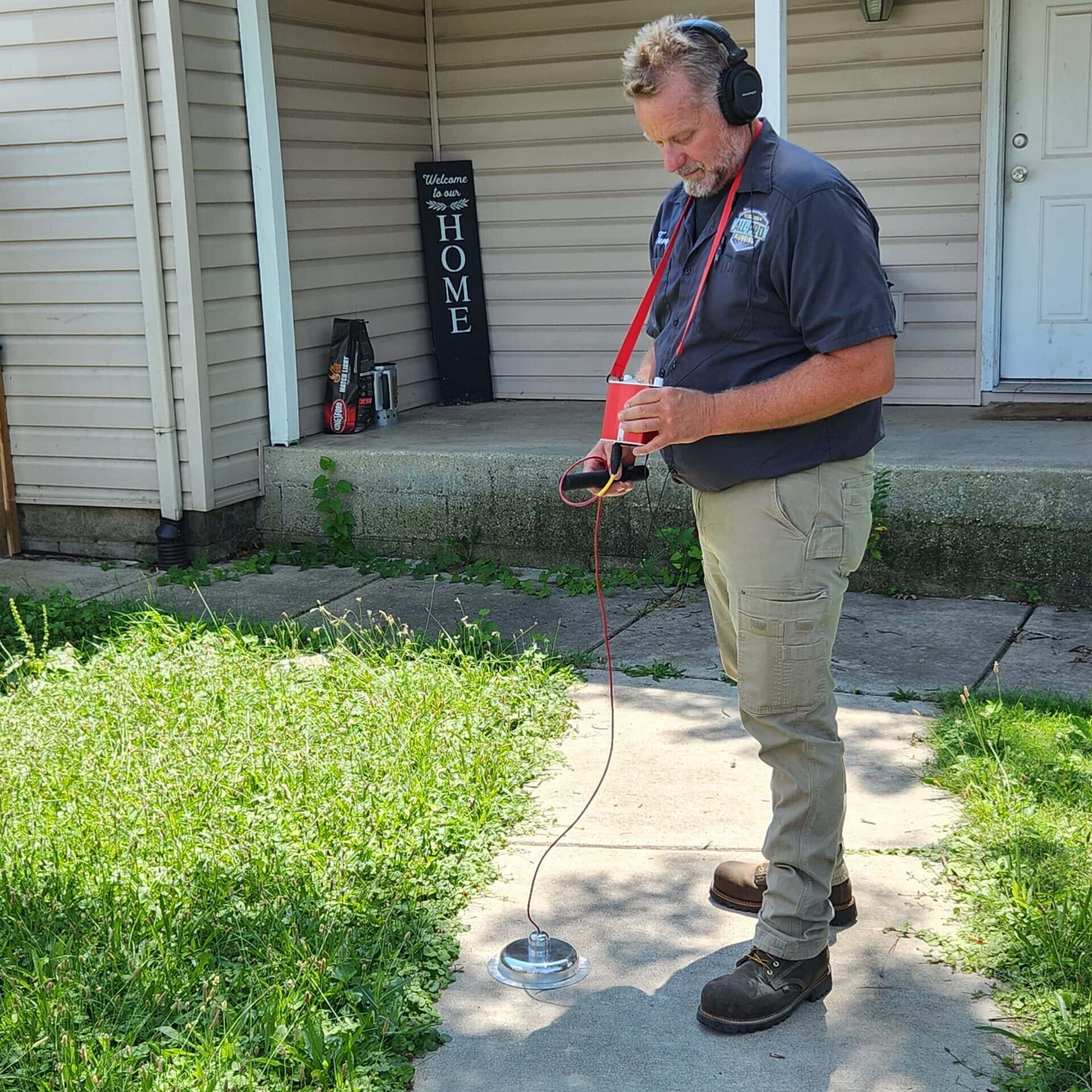 19 Leak Detection Home Interior Exterior Slab Water Wet All-Pro Plumbing technician using advanced acoustic listening device on a sidewalk to detect hidden exterior water leaks at a residential home in Kokomo, IN