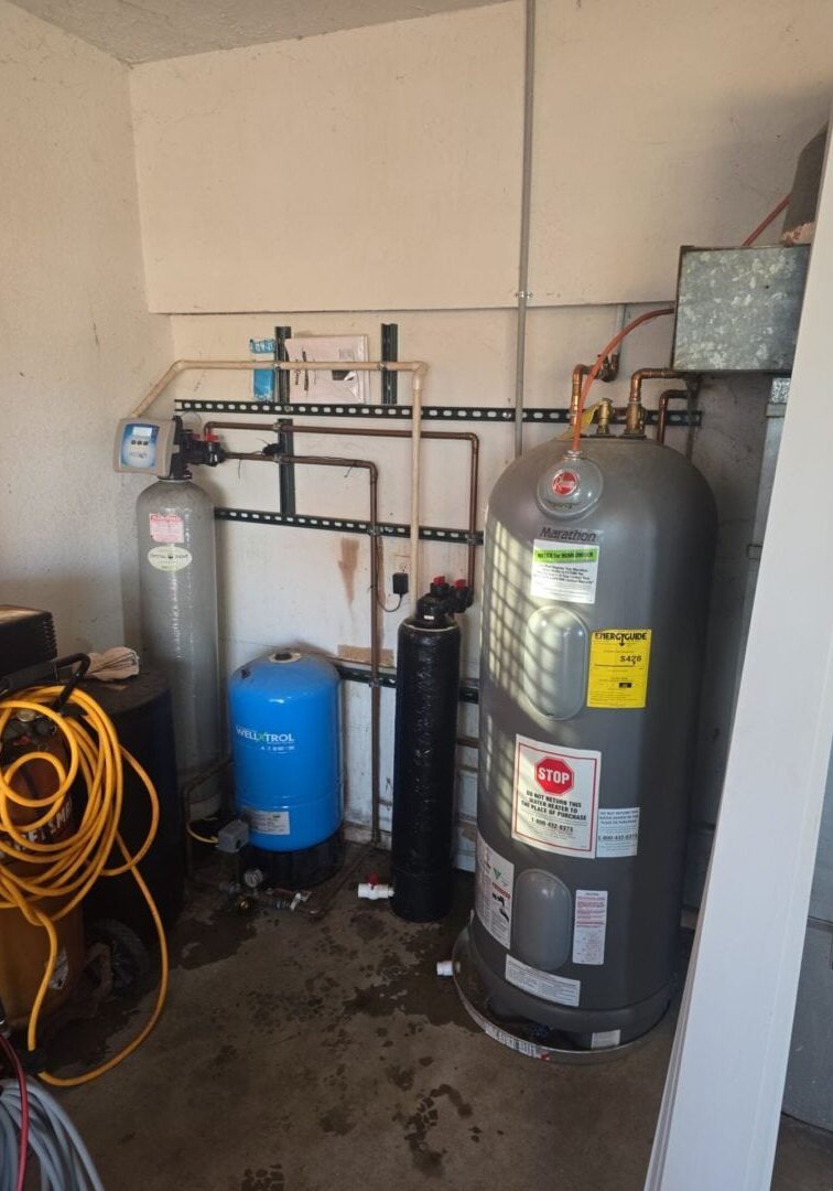 Utility room with a water heater, water conditioner, and well water plumbing system, featuring a tankless water heater. All-Pro Plumbing, Kokomo, IN.
