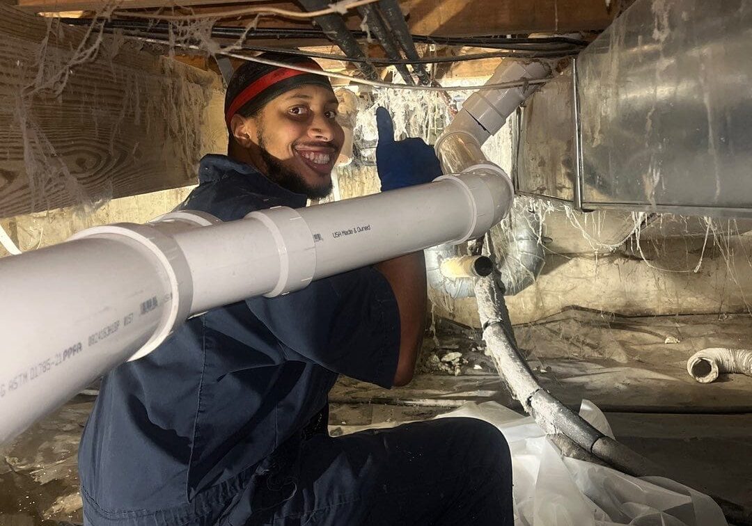23 Crawl Space Drain Line Repipe DWV PVC Replace Repair Licensed Plumbers Licensed All-Pro Plumbing technician smiling while repiping a DWV PVC drain line in a tight crawl space for a home in Kokomo, IN
