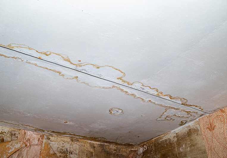 Damage ceiling from water pipelines leakage. Housing problem concep Ceiling with widespread water stains and peeling paint from a hidden, obscure plumbing leak, indicating water damage and the need for leak detection and repair by All-Pro Plumbing in Kokomo, IN