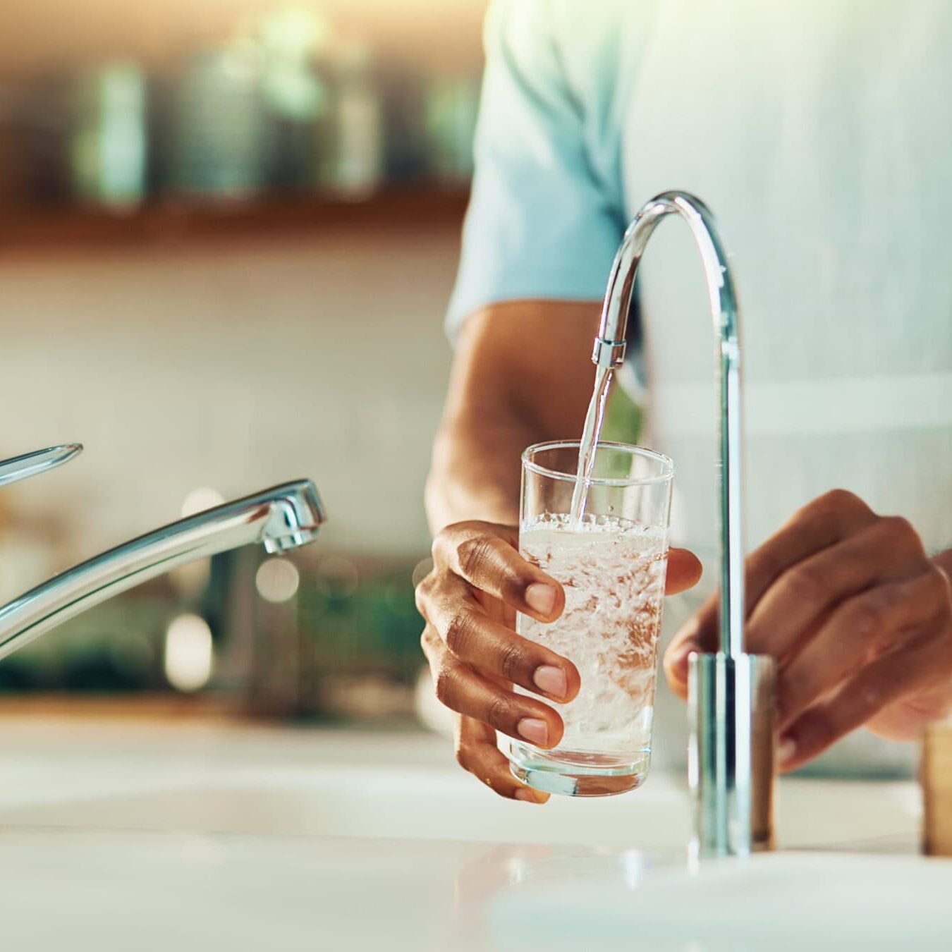 Person, tap and hands with glass of water in kitchen for fresh drink, liquid and hydration. Sink closeup, thirsty or pouring pure beverage in container for nutrition, drinking or filtration in home Person filling a clear glass with clean, filtered drinking water from a dedicated faucet, representing healthy water quality from All-Pro Plumbing's advanced filtration systems in Kokomo, IN