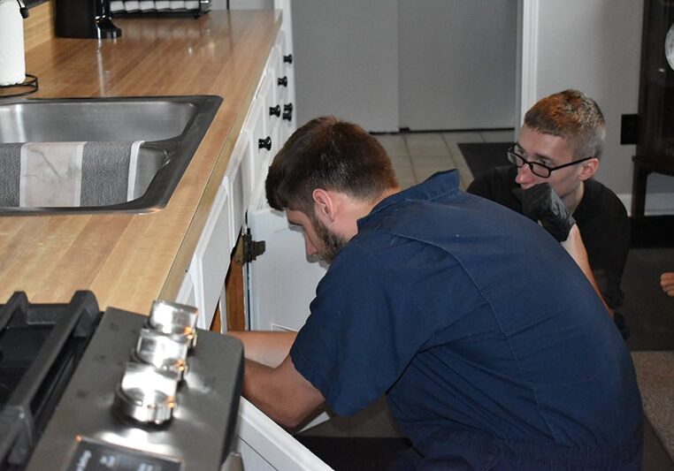 All-Pro Plumbing technicians performing an undersink plumbing repair, showcasing their in-field expertise and training