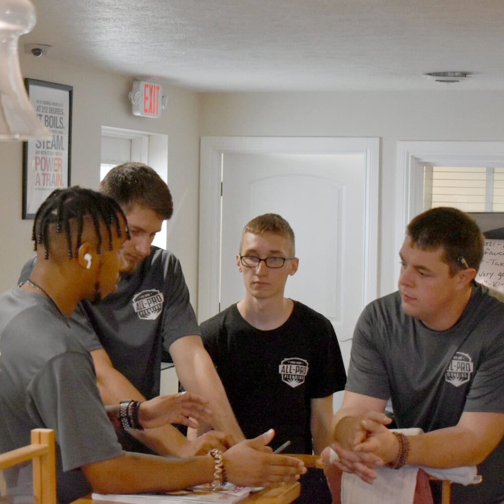 A group of All-Pro Plumbing technicians and plumbers collaborating and planning in their Kokomo office for a repair job